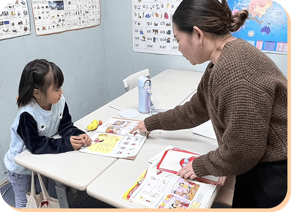 英語教材を使って指導を受ける子どもと先生