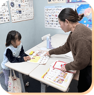英語教材を使って指導を受ける子どもと先生
