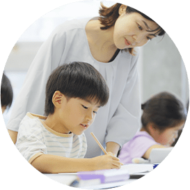 勉強に集中する子どもとサポートする先生
