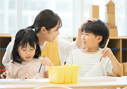 絵の具で遊ぶ子どもたちと見守る先生