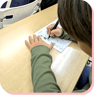 机に向かって文字を書く子どもの手元