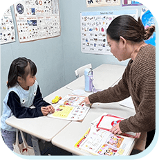 英語教材を使って指導を受ける子どもと先生